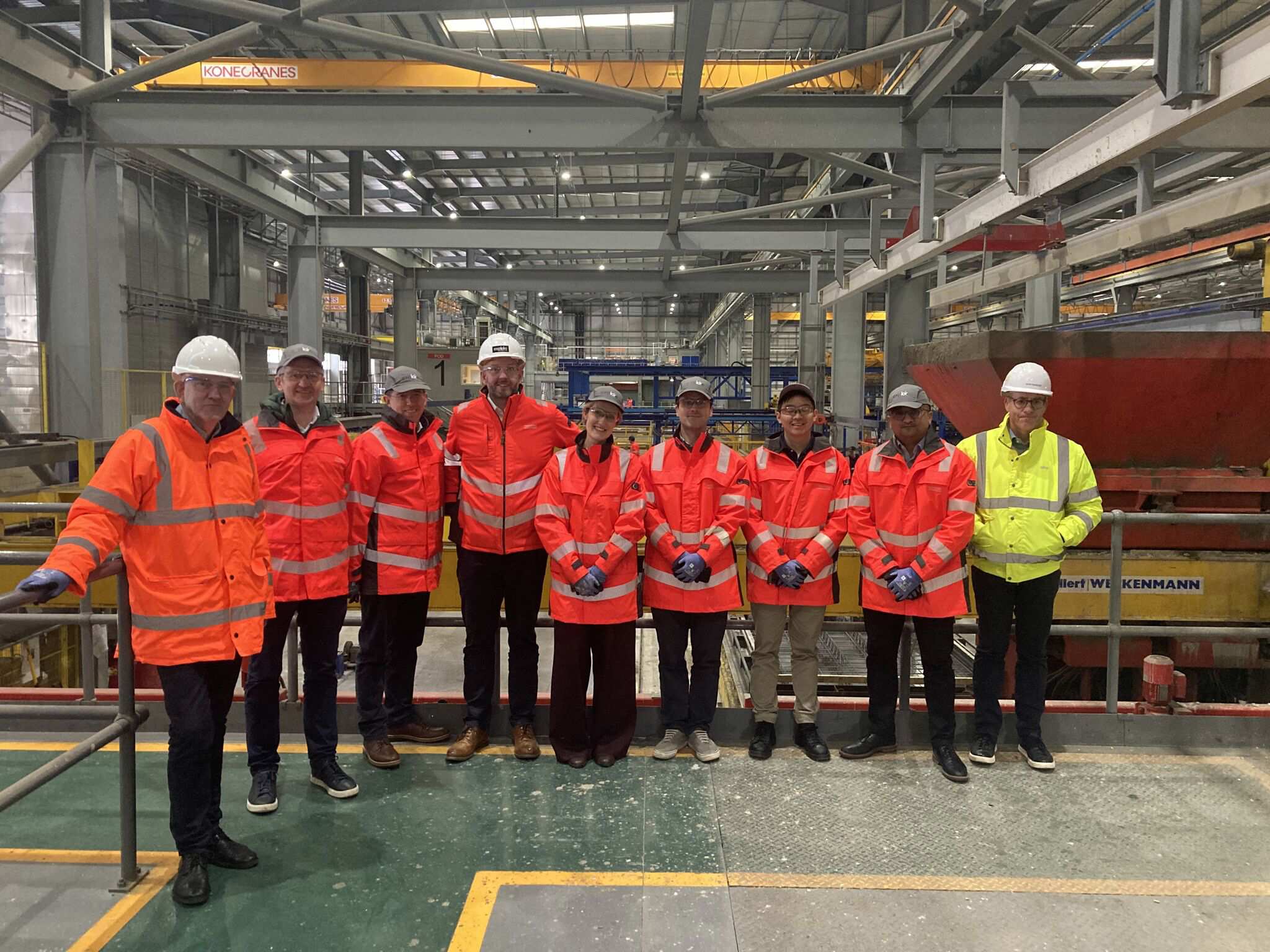 People in hi-vis and hard hats on a site tour of a logistics building